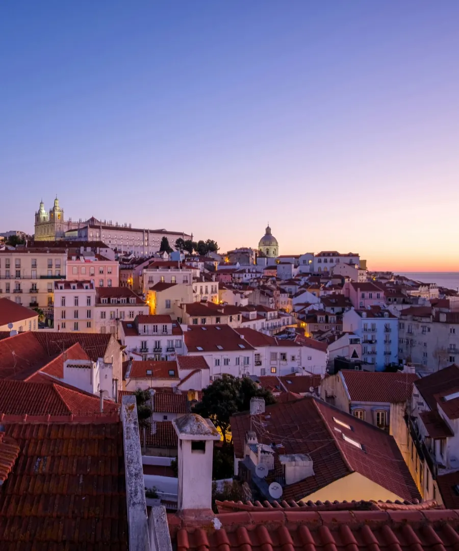 The rooftops of Alfama at dusk, with the Tagus beyond.