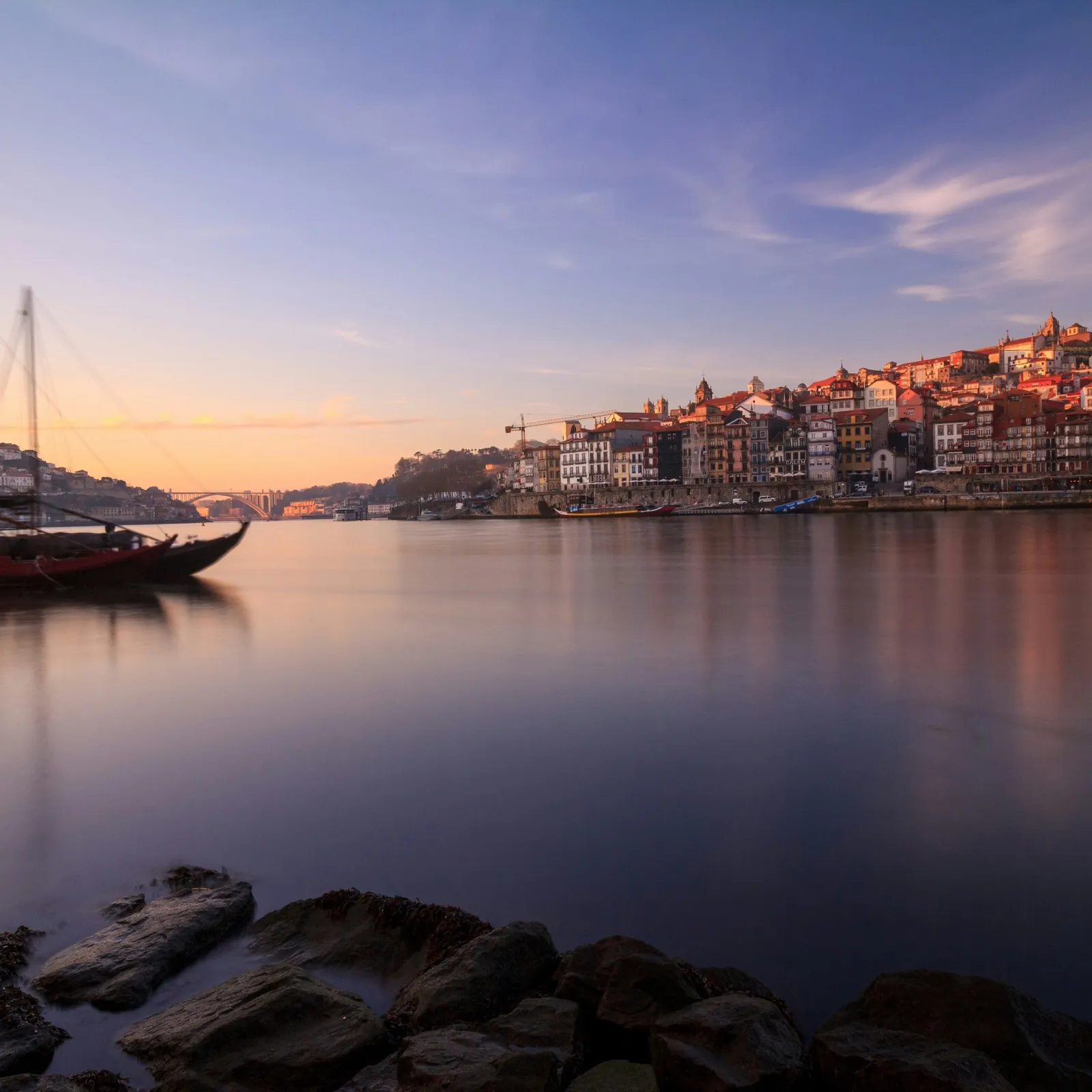 Rabelo boats on the Douro at sunrise, with the Ribeira of Porto beyond.