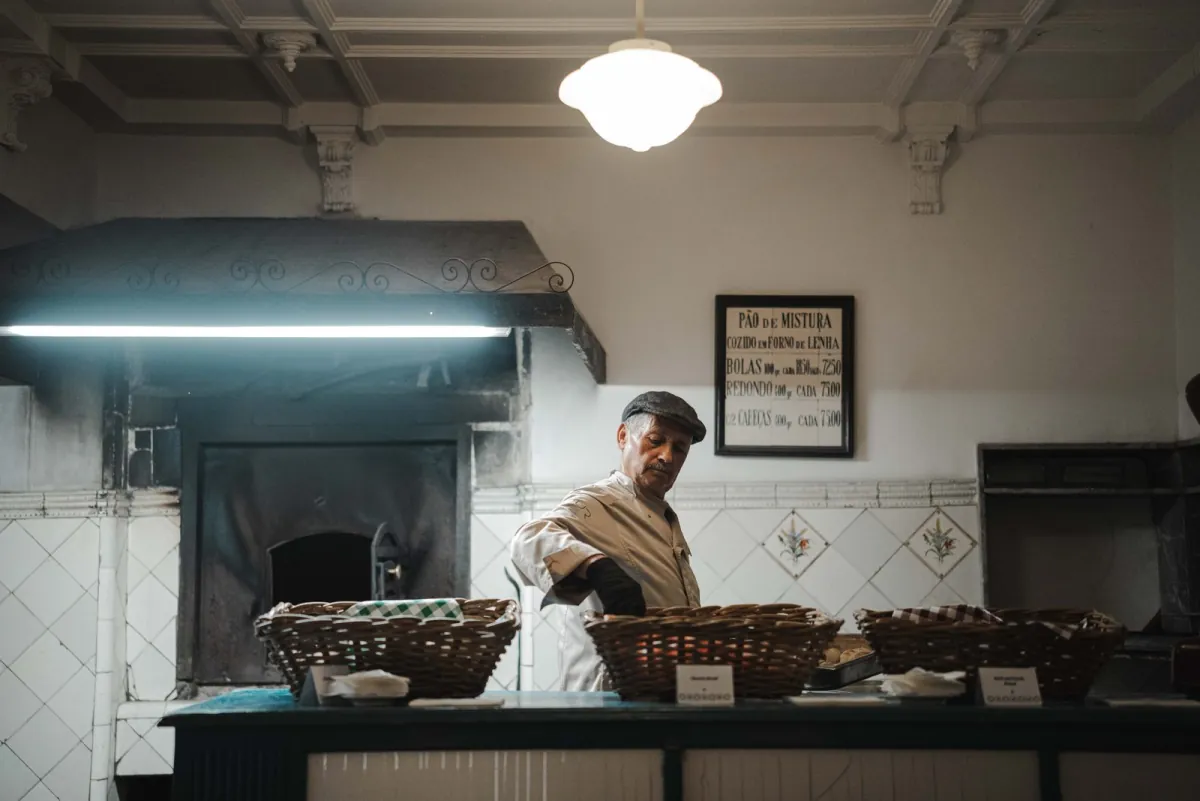 A baker setting out baskets of bread in an old bakery.